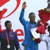 Geoffrey Mutai (R) of Kenya waves after winning gold in the men's  event of Delhi half Marathon, along with silver medallist Lelisa Desisa (L) of Ethiopia and bronze medal winner Yacob Yarso of Ethopia during the victory ceremony , in New Delhi