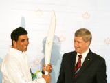 Canadian Prime Minister Stephen Harper and  Akshay Kumar pose with a jacket, which will be worn by torchbearers for the 2010 Winter Olympics